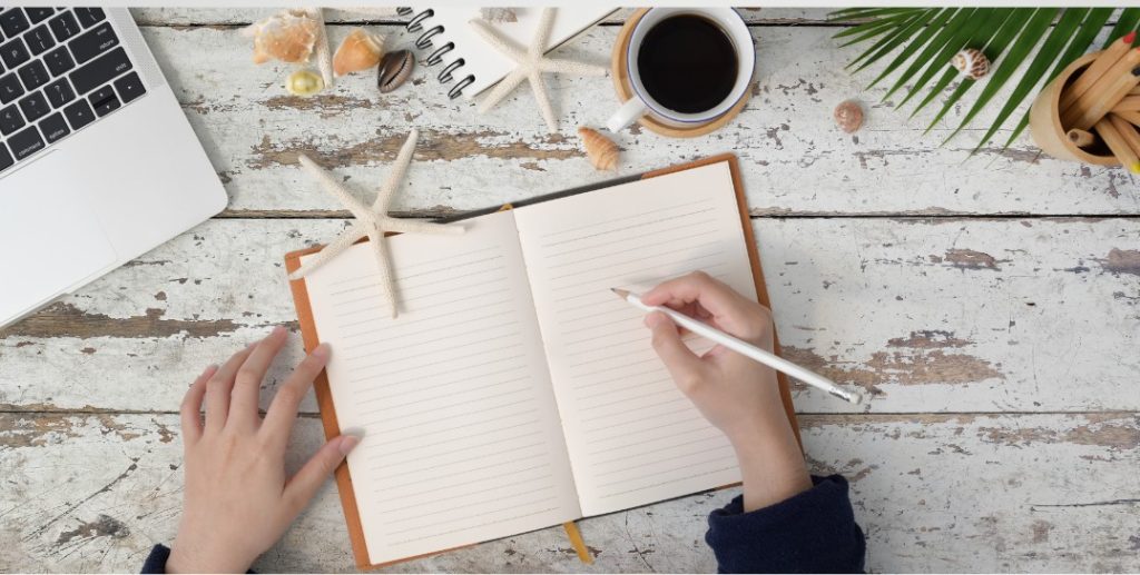 Escribiendo en un cuaderno y tomando un café